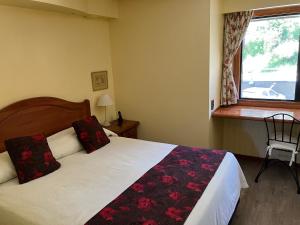 Un dormitorio con una cama con almohadas rojas y una ventana en Bahía Manzano Resort en Villa La Angostura