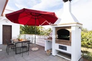 a patio with a fireplace and a red umbrella at Tegas: Tacoronte, by Nivariahost in Tacoronte