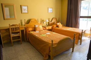 a bedroom with two beds and a desk and a chair at La Casona del Pinar Albergue in San Rafael