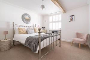 a bedroom with a bed and a chair and a mirror at Bijou Cottage in Deal