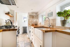 a kitchen with white cabinets and a sink at Bijou Cottage in Deal