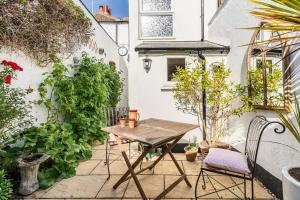 a small patio with a wooden table and chairs at Bijou Cottage in Deal