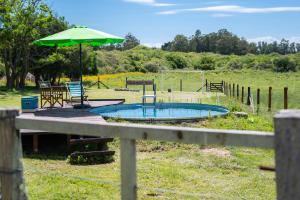 a small pool with an umbrella and a table and chairs at Chacra La Mondiola del Este in Ciudad de la Costa +19 photos