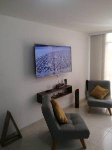 a living room with a chair and a tv on a wall at Apartamento amoblado - Armenia Quindío. in Armenia