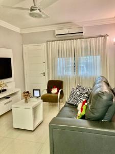 a living room with a leather couch and a tv at Casa centro Falls in Foz do Iguaçu