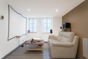 uma sala de estar com um sofá branco e uma mesa em Appartement spa privatif et cinéma centre ville em Metz