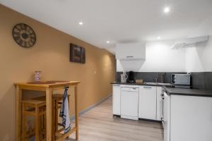 a kitchen with white cabinets and a table and a clock at Appartement spa privatif et cinéma centre ville in Metz