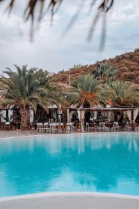 einen großen Pool mit Palmen, Tischen und Stühlen in der Unterkunft Il Monastero in Geremèas