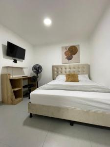 1 dormitorio con 1 cama, escritorio y TV en Hotel Boutique San Joaquin Plaza en Medellín