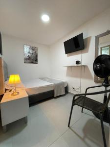 a bedroom with a bed and a chair and a tv at Hotel Boutique San Joaquin Plaza in Medellín