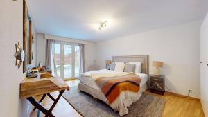 a bedroom with a bed and a table and a window at Le Belvedere By Alaïa in Crans-Montana