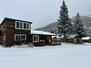 ein Blockhaus mit Schnee auf dem Boden in der Unterkunft Deer Lodge in Red River