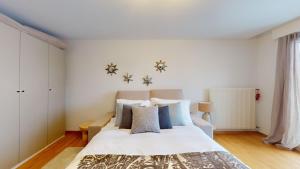 ein Schlafzimmer mit einem weißen Bett mit blauen Kissen in der Unterkunft Le Belvedere By Alaia in Crans-Montana