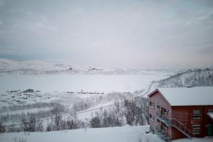 里克斯格倫森的住宿－Ski in ski out lägenhet med fantastisk utsikt，雪地中的红色建筑,享有田野的景色