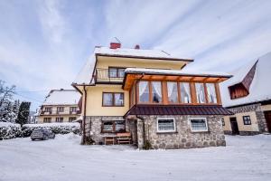 a house with snow on the ground in front of it at U Capka in Poronin