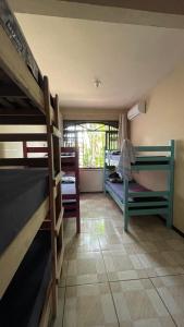a room with three bunk beds and a window at Fica, Vai ter Bolo Hostel in Itajaí