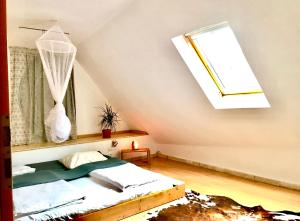 Schlafzimmer mit einem Bett mit einem Fenster und einem Dachfenster in der Unterkunft Transylvania Escape in Richişu