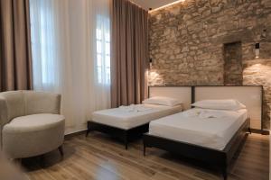 une chambre d'hôtel avec deux lits et une chaise dans l'établissement Helin's Hostel by Backpackers, à Berat