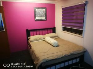 Un dormitorio con una pared rosa y una cama en Homestay Teratak Tuan Muda, en Air Molek