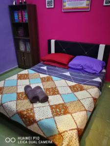 Cama en habitación con pared púrpura en Homestay Teratak Tuan Muda, en Air Molek