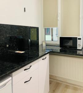 eine Küche mit weißen Schränken und einer schwarzen Arbeitsplatte in der Unterkunft Center Lviv Avenue 23 in Lwiw
