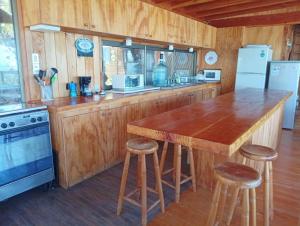 una cocina con encimera de madera con taburetes. en Casa Playa Puertecillo, en Puertecillo