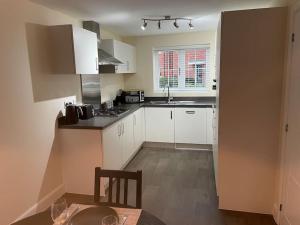 a kitchen with white cabinets and a table and a dining room at Beautiful Family Home in Mickleover