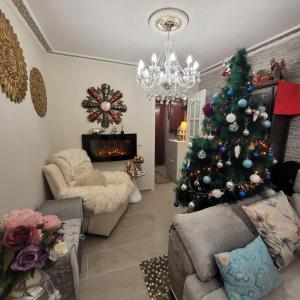 een woonkamer met een kerstboom en een kroonluchter bij Shared accommodation a room with a view of the garden in Sevilla