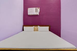 a bed in a room with a purple wall at Hotel O Chaudhary Hotel in Tatārpur +41 photos