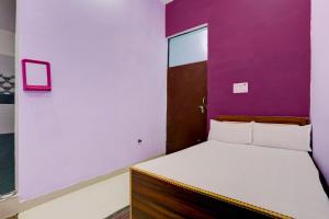 1 dormitorio con 1 cama con pared morada en OYO SS Hotel en Alwar