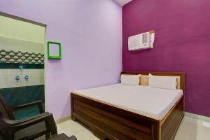 1 dormitorio con cama y pared púrpura en OYO SS Hotel en Alwar