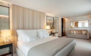Wine & Books Porto Hotel في بورتو: غرفة نوم بسرير ابيض كبير واريكة