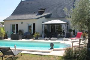 Casa con piscina con sillas y sombrilla en Le Champ De La Ferme en Saint-Gervais en-Belin