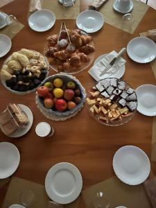 einen Tisch mit Teller und Schalen verschiedener Arten von Lebensmitteln in der Unterkunft Casa Nina Bologna Centro in Bologna