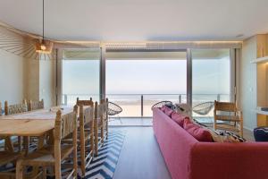 une salle à manger avec un canapé rose et une table dans l'établissement Boutique Rentals- AL MAR Beachfront, à Póvoa de Varzim