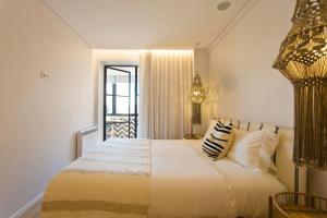 - une chambre avec un grand lit blanc et des oreillers dans l'établissement Boutique Rentals- AL MAR Beachfront, à Póvoa de Varzim