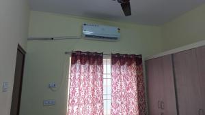 Zimmer mit einem Fenster mit Vorhängen und Klimaanlage in der Unterkunft Stayzilla Santhoshini Homes 2 BHK in Vellore