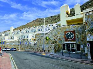 een gebouw op een straat met een berg op de achtergrond bij Residence Puerto Rico in Puerto Rico de Gran Canaria