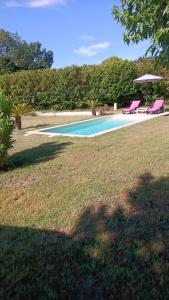 una piscina con 2 sillas rosas en un patio en gite du bois doré, en Les Vignères