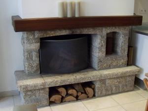 a stone fireplace with a tv and logs at Charmante Maison de Pêcheur en baie du Mont Saint Michel in Genêts