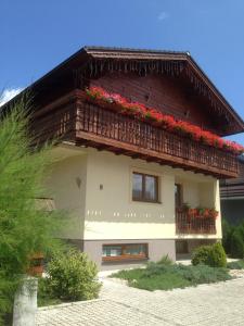 una casa con un balcone con fiori rossi di Guest house Fleurs a Liptovský Mikuláš