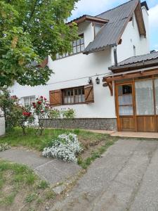 a white house with wooden doors and windows at La Casa de la Isla in San Martín de los Andes