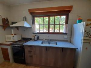 uma cozinha com um lavatório e um frigorífico branco em La Casa de la Isla em San Martín de los Andes