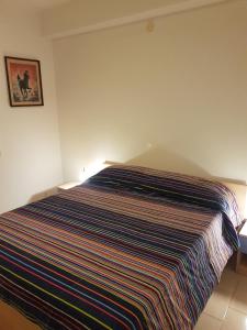 a bedroom with a bed with a striped blanket on it at SANT'ALESSIO_BAY in Santa Margherita-Sant'Alessio Siculo