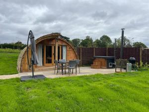 a circular hut with a table and chairs and an umbrella at Wimbish Hall Cabins in Wimbish