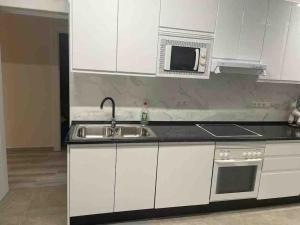 una cucina con armadi bianchi, lavandino e forno a microonde di apartamento luxury en Fuengirola a Fuengirola