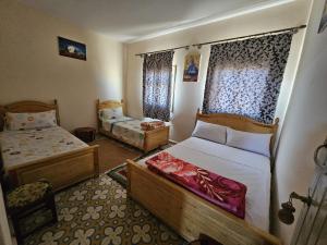a small bedroom with two beds and a window at Panorama chez Hamid in Rissani