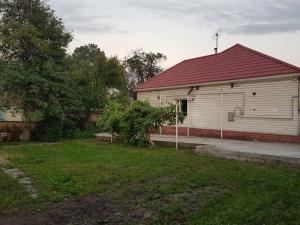 a white house with a red roof and a yard at Garden House in Almaty