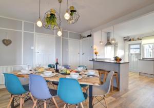 a dining room with a table and blue chairs at Fourwinds in Gwbert