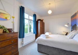 a bedroom with a bed and a dresser and a window at Fourwinds in Towyn